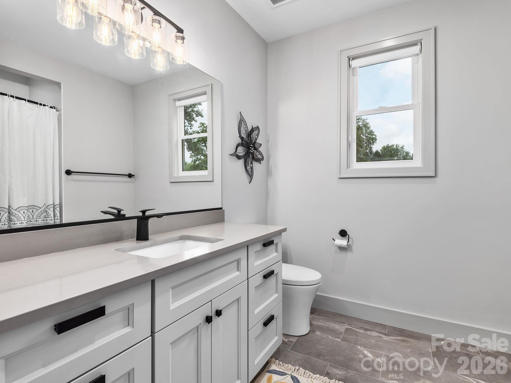 7 Copper Mill Court Candler, NC 28715 - Photo 27 of 32 a bathroom with a granite countertop sink mirror and toilet