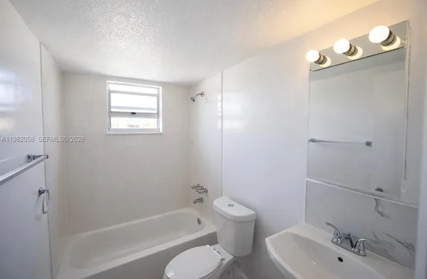 a bathroom with a bathtub shower sink vanity and toilet