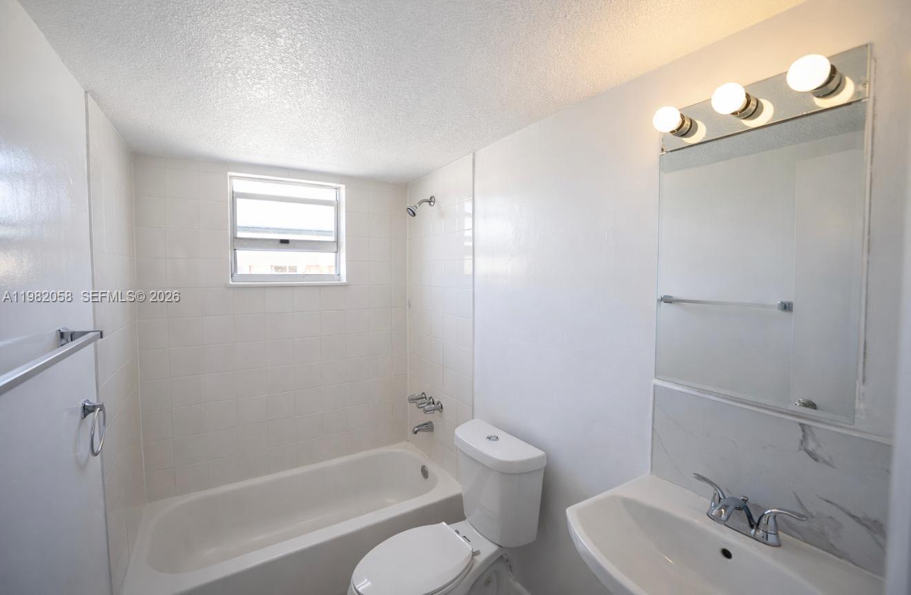 2315 West Okeechobee Road, Unit 202 Hialeah, FL 33010 - Photo 9 of 10 a bathroom with a bathtub shower sink vanity and toilet