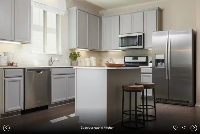 a kitchen with stainless steel appliances a sink a stove a refrigerator cabinets and a window