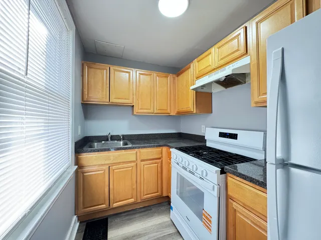 a kitchen with stainless steel appliances granite countertop a sink a stove and a refrigerator