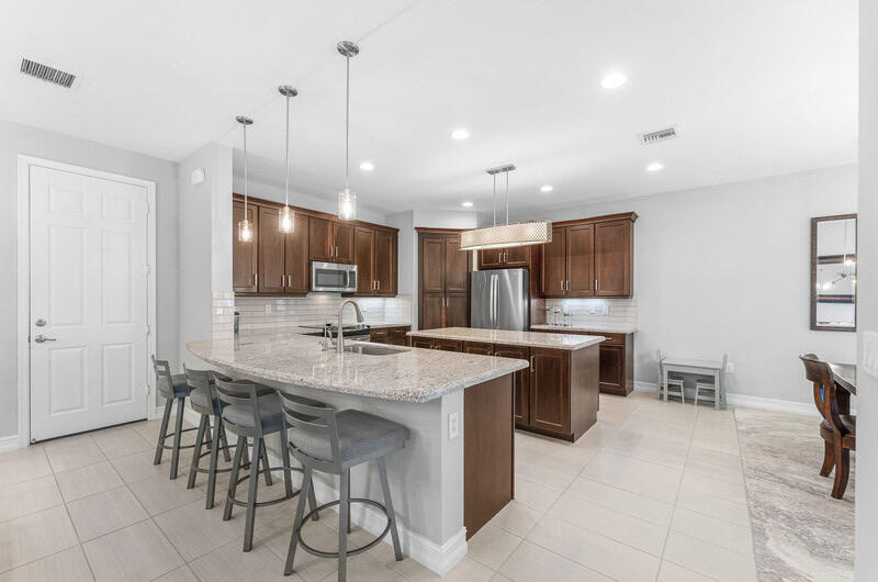 8091 Snowflake Obsidian Trail Delray Beach, FL 33446 - Photo 8 of 35 a kitchen with stainless steel appliances kitchen island granite countertop a table chairs and a sink