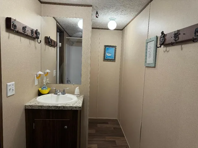 a bathroom with a granite countertop sink a mirror and shower