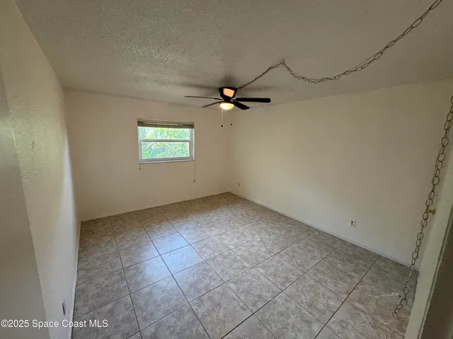 an empty room with windows and ceiling fan