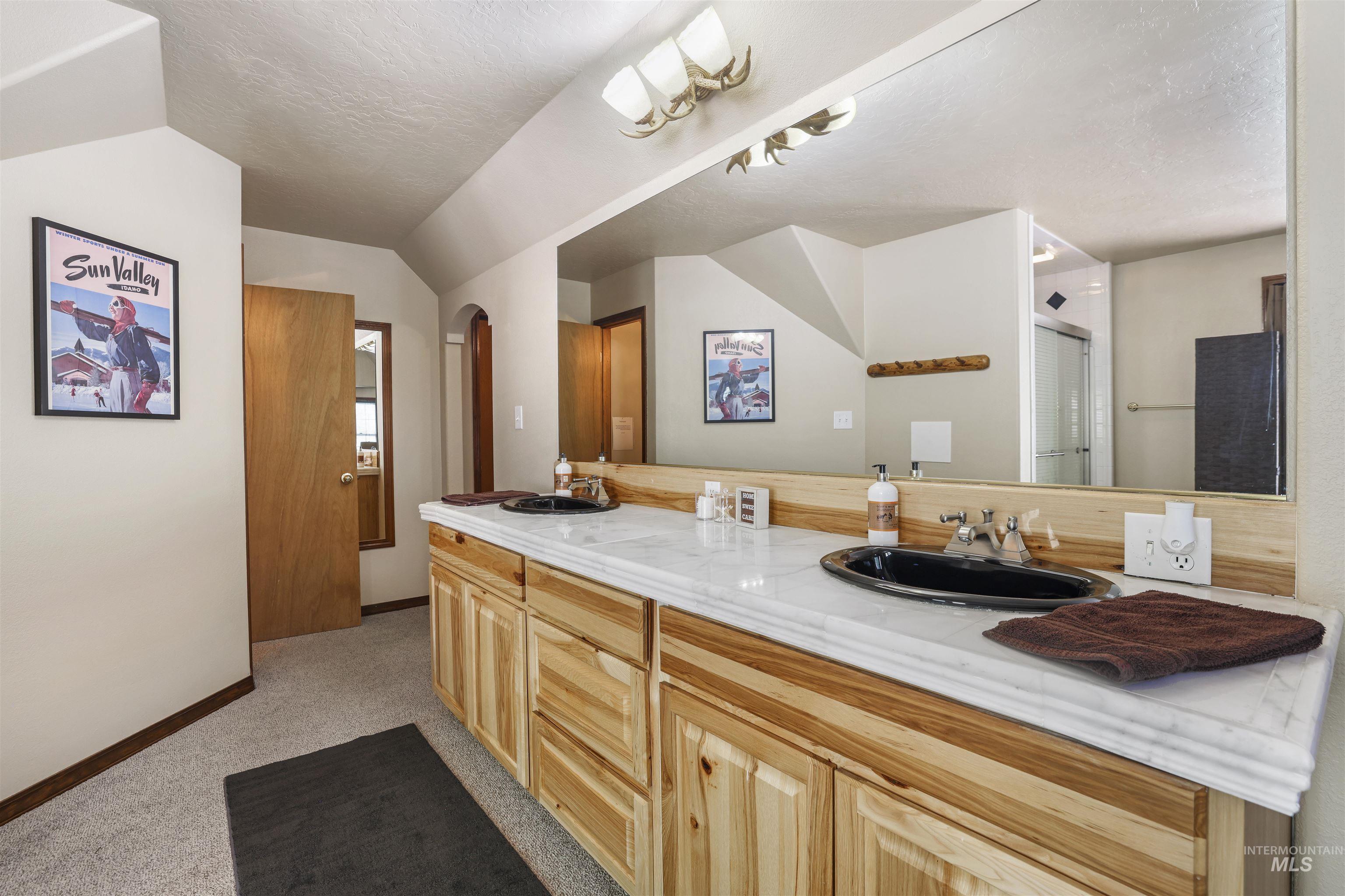 224 Dakota Road Mountain Home, ID 83647 - Photo 31 of 50 Double vanity featuring natural wood cabinetry, light-colored countertop, and two black oval sinks