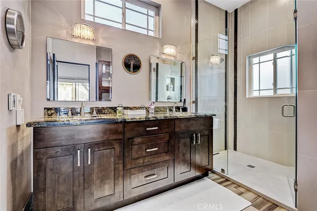 a bathroom with a granite countertop sink a mirror and a shower