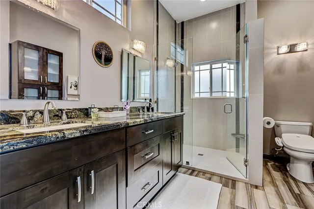 a bathroom with a granite countertop sink mirror vanity and toilet