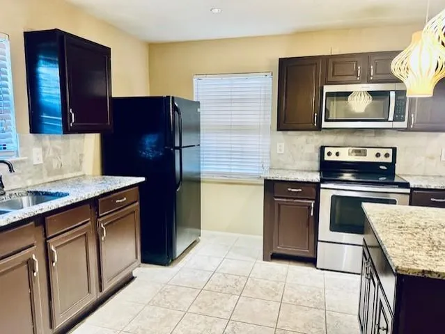 a kitchen with stainless steel appliances granite countertop a stove microwave and sink