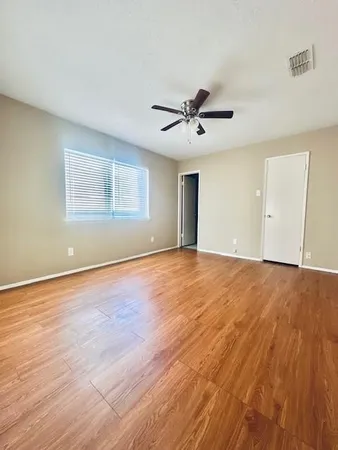 a view of an empty room with a window and wooden floor