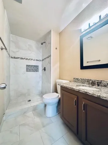a bathroom with a granite countertop sink toilet and shower