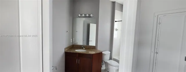 a bathroom with a granite countertop sink toilet and a mirror