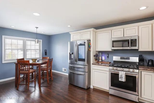 a kitchen with granite countertop stainless steel appliances a dining table and chairs