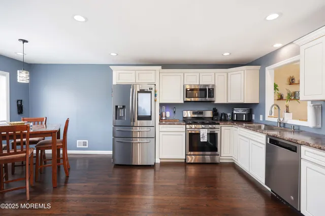 a kitchen with refrigerator and wooden floor
