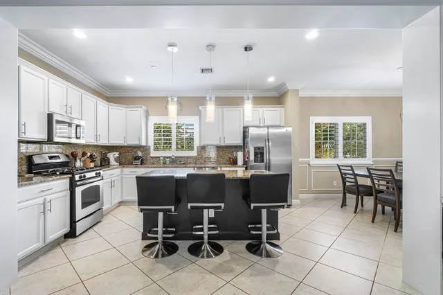 a kitchen with stainless steel appliances granite countertop a refrigerator a stove a sink and a refrigerator