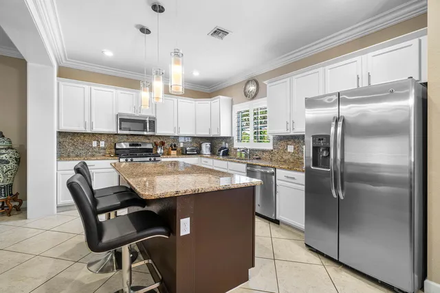 a kitchen with stainless steel appliances granite countertop a stove top oven a sink dishwasher a dining table and chairs with wooden floor