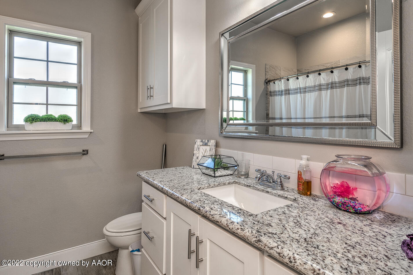 6103 Bowery Amarillo, TX 79119 - Photo 18 of 23 a bathroom with a granite countertop sink a toilet a mirror and a window