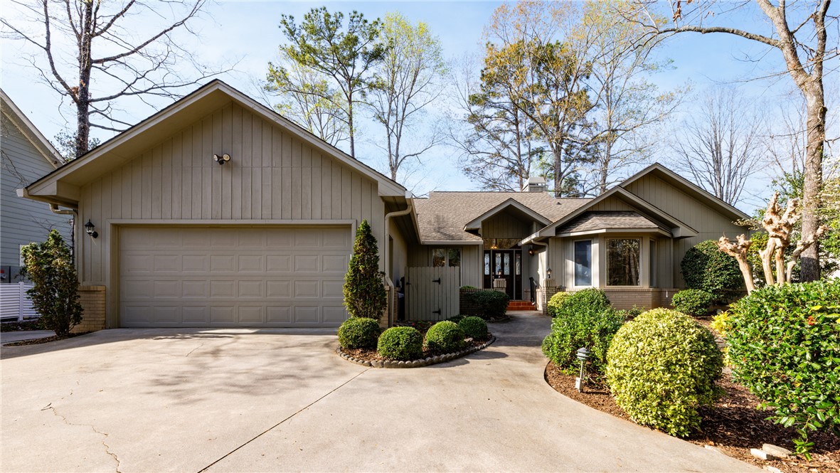 This residence features a spacious attached garage and a welcoming facade amidst lush landscaping.