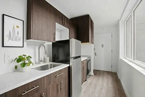 a kitchen with stainless steel appliances a sink a refrigerator a counter space and cabinets