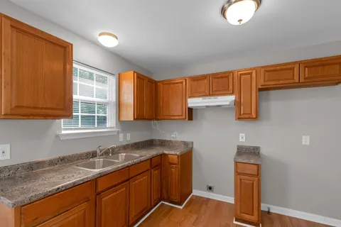 a kitchen with granite countertop wooden cabinets a sink and a window
