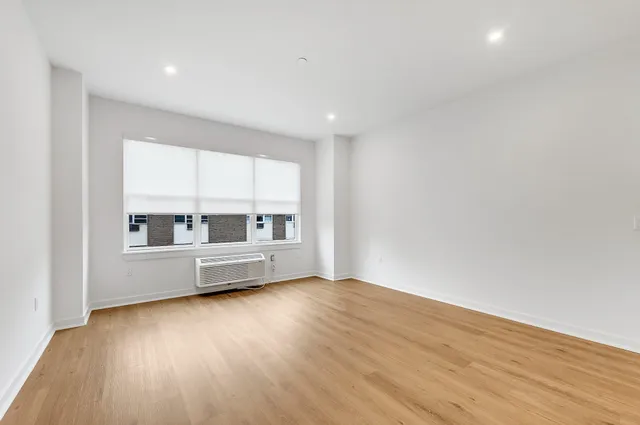 a view of an empty room with a window and wooden floor