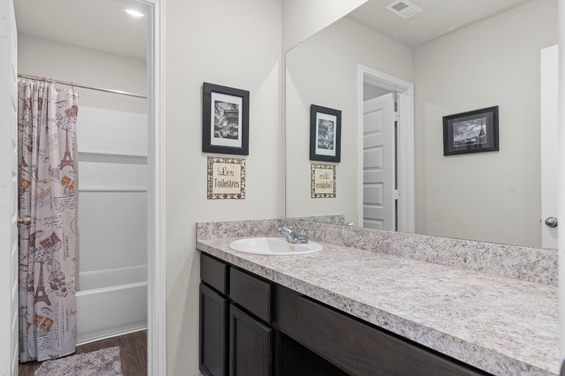 22565 Cormorant Court Splendora, TX 77372 - Photo 23 of 31 a bathroom with a granite countertop sink a mirror a bathtub and shower