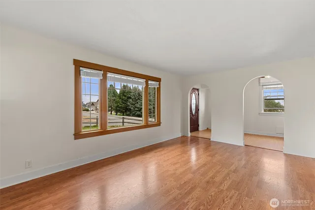 a view of an empty room with window and wooden floor