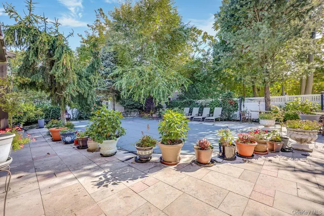 a view of a patio with table and chairs potted plants and large tree