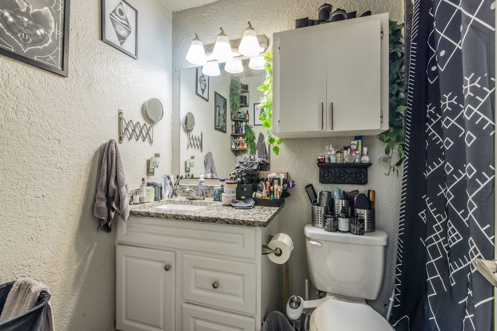 1008 Milford Way Austin, TX 78745 - Photo 16 of 40 Bathroom featuring a white vanity with a granite-style countertop, a built-in wall cabinet, a mirror, and a light fixture with three sconces