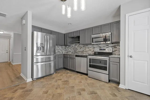 a kitchen with stainless steel appliances granite countertop a stove refrigerator and microwave