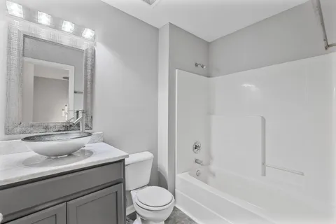 a bathroom with a granite countertop sink a toilet a mirror and bathtub