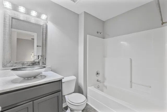 a bathroom with a granite countertop sink a toilet a mirror and bathtub