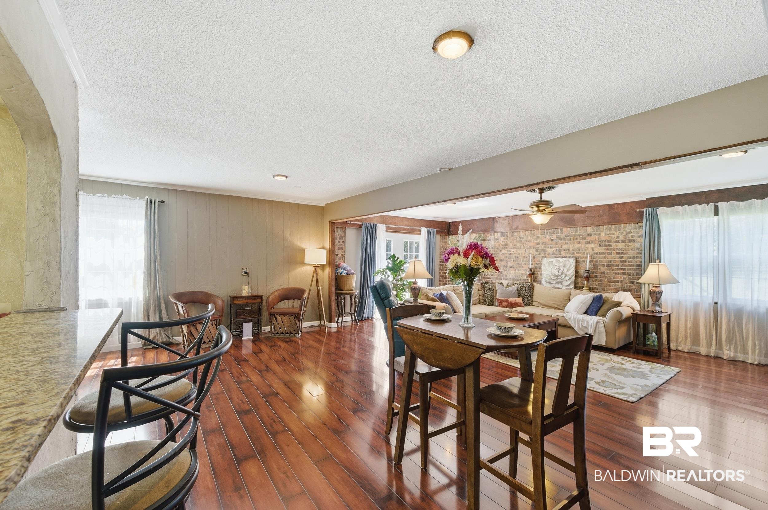51620 Robert White Road Bay Minette, AL 36507 - Photo 17 of 81 Spacious living area featuring rich wood-finish flooring throughout, a stone-finish breakfast bar, and a prominent brick accent wall