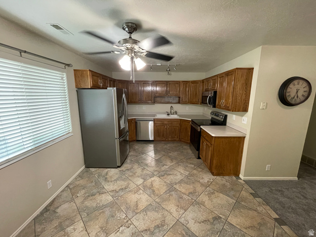 101 1501 Monroe, Unit 101 Ogden, UT 84404 - Photo 5 of 24 Kitchen with stainless steel appliances, light countertops, ceiling fan, wood finish cabinetry, and a textured ceiling