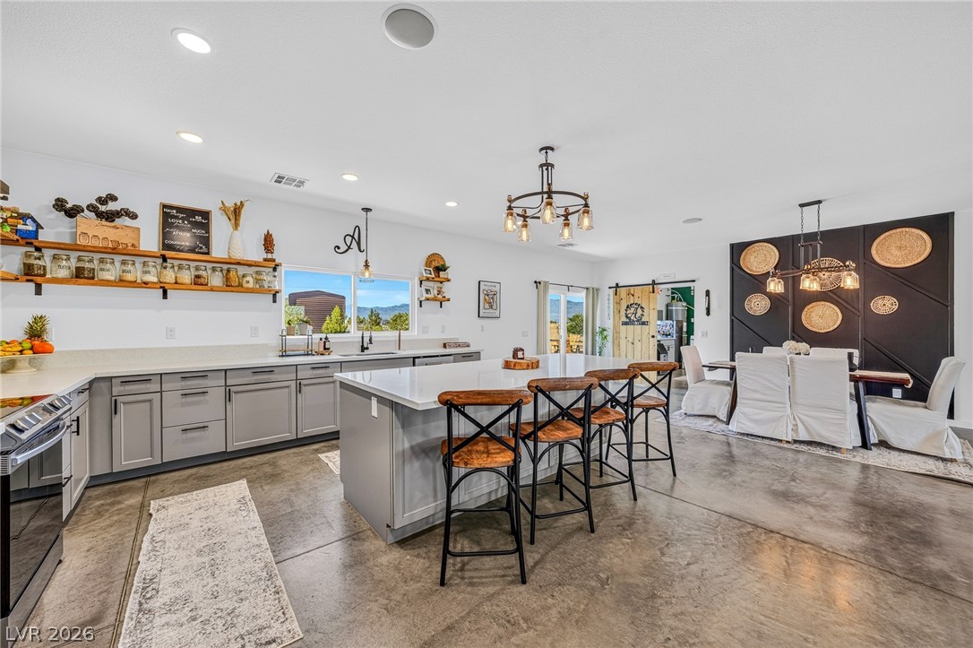4080 Magnet Road Pahrump, NV 89048 - Photo 5 of 28 Polished concrete floors and a substantial central island anchor this open-concept kitchen and dining area.