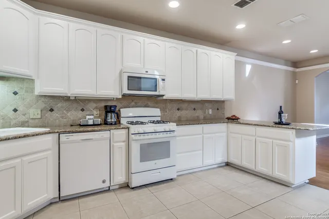 a kitchen with white cabinets sink and stove