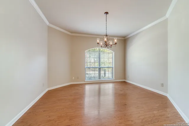 a view of an empty room with window and wooden floor