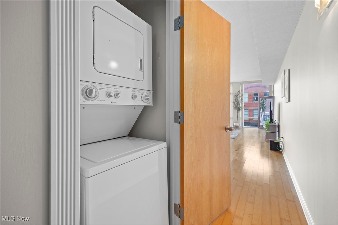 2222 Detroit Avenue, Unit 519 Cleveland, OH 44113 - Photo 21 of 30 Washroom featuring laundry area, light wood-style floors, stacked washer / drying machine, and baseboards