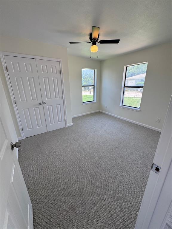 1736 Ransom Terrace Fort Worth, TX 76112 - Photo 18 of 27 Neutral-toned room featuring a ceiling fan with integrated lighting, two windows, wall-to-wall carpeting, white baseboards, and a bi-fold closet door
