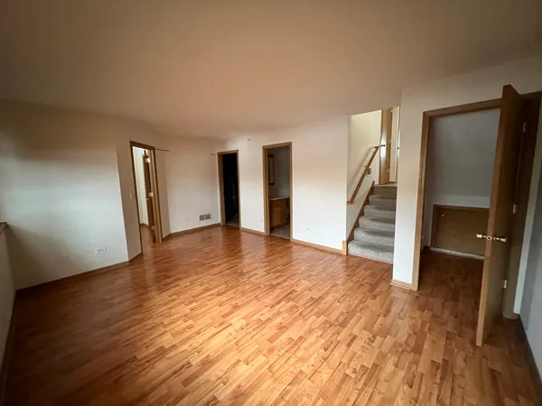 a view of an empty room with wooden floor and stairs