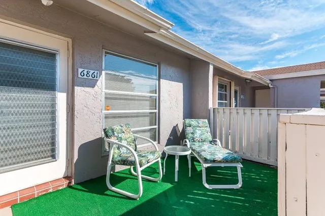 a view of a chair and table in backyard of the house