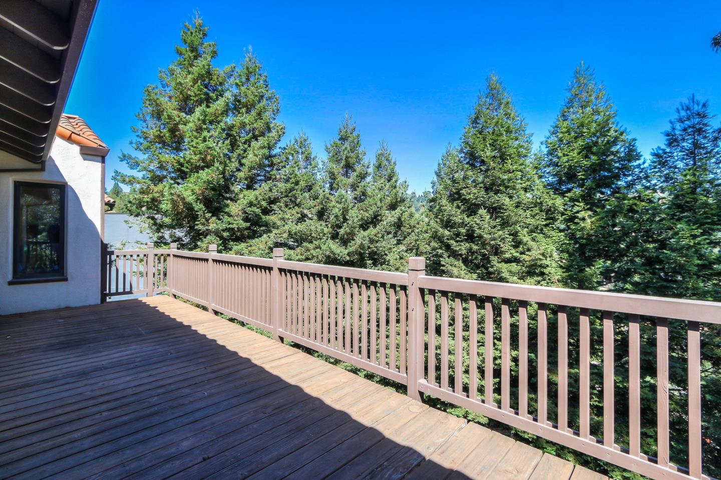 6840 Buckingham Boulevard Berkeley, CA 94705 - Photo 13 of 50 a balcony with wooden floor and trees in the background