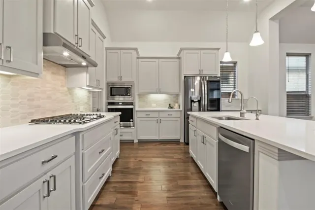 a kitchen with white cabinets and appliances