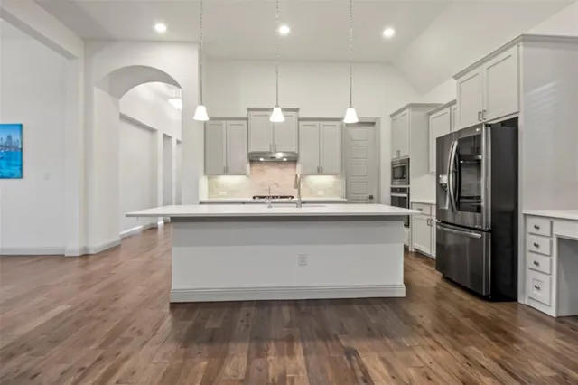 a large white kitchen with a refrigerator a sink and a stove