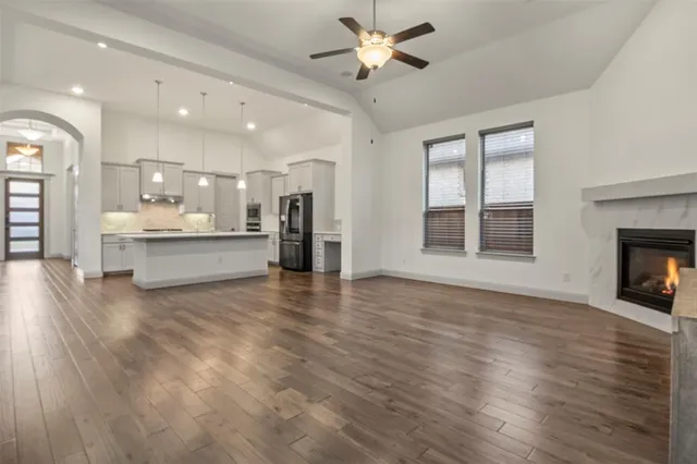 a view of a livingroom with a fireplace a ceiling fan and windows
