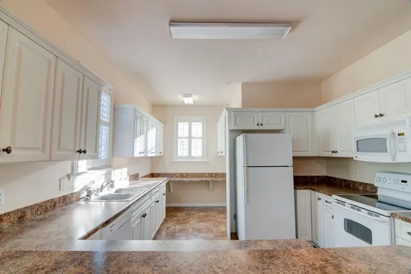a kitchen with refrigerator a stove a sink and white cabinets