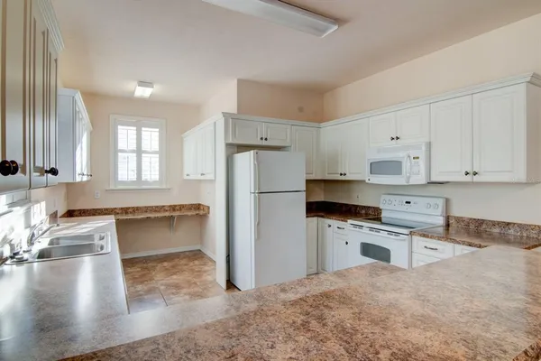 a kitchen with granite countertop a stove a sink and a refrigerator