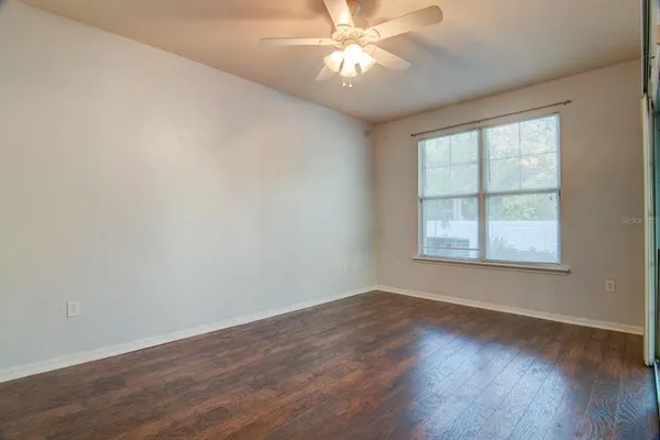 a view of an empty room with wooden floor and a window