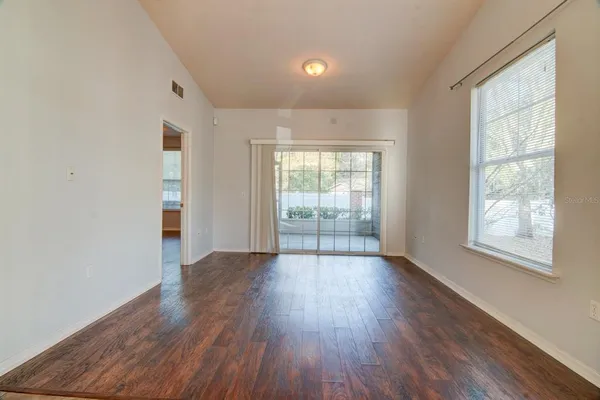 an empty room with wooden floor and windows