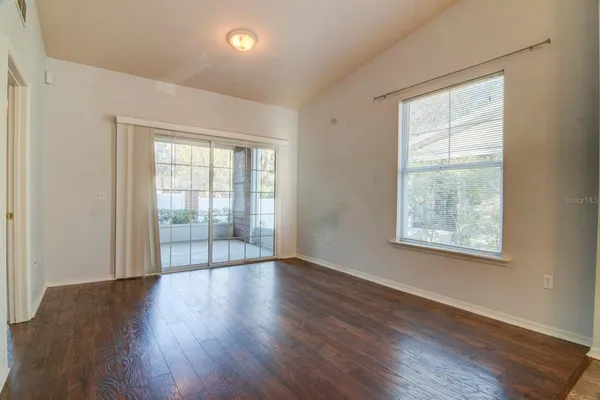 a view of an empty room with wooden floor and a window