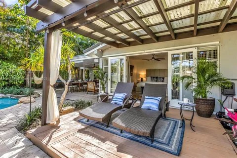 a view of a patio with table and chairs potted plants with wooden floor and floor to ceiling window
